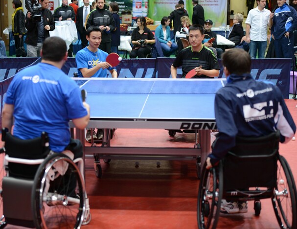 Der Fuldaer TTBL-Spieler Wang Xi (links) im Rollstuhl-Doppel mit seinem Trainer Qing Yu Meng gegen die Paralympischen Spitzensportler Selcuk Cetin (links) und Holger Nikelis (©sport grenzenlos)